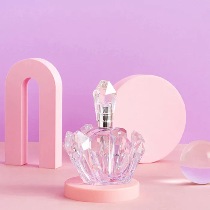 Crystal perfume bottle on a pink platform with a soft purple background