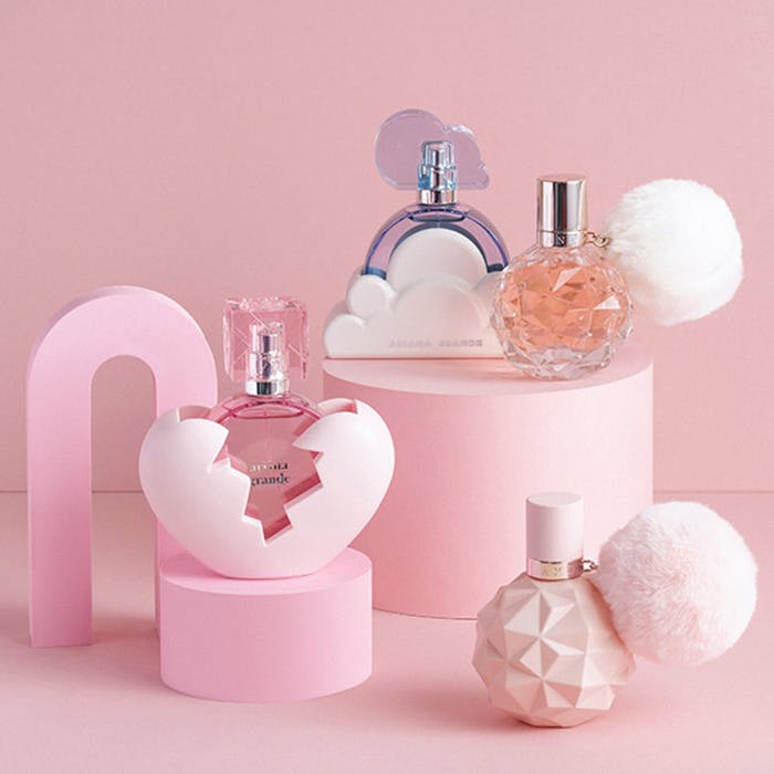 Collection of perfume bottles on pink stands with a soft pink background