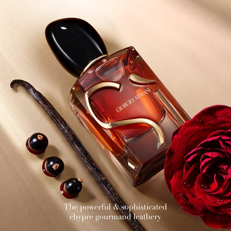 Perfume bottle with a vanilla bean, black currant, and red rose on a beige background