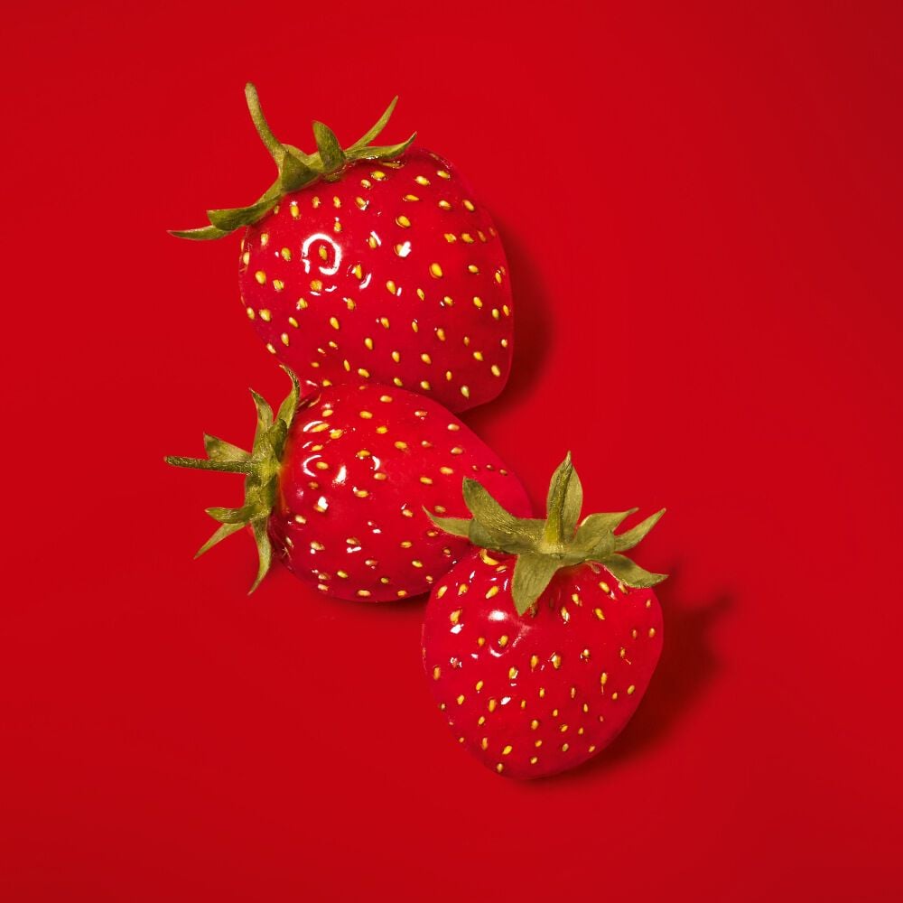 Three strawberries arranged on a red background