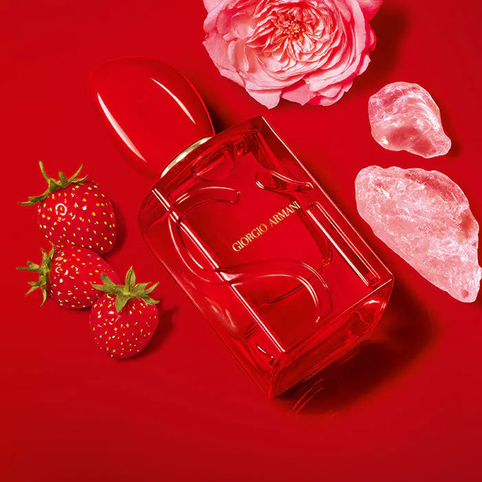 Red Giorgio perfume bottle with pink flowers, strawberries, and pink stones on a red background