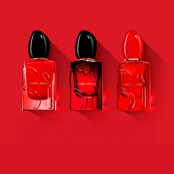 Three red perfume bottles with black caps on a red background