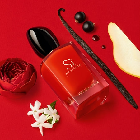 Red perfume bottle with vanilla bean, rose, and flowers on a red background