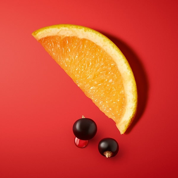 Orange wedge with two black berries on a red background