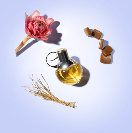 Perfume bottle with a flower and jewelry on a light blue background