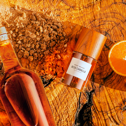 Two bottles of on a wooden surface with spices and an orange slice.