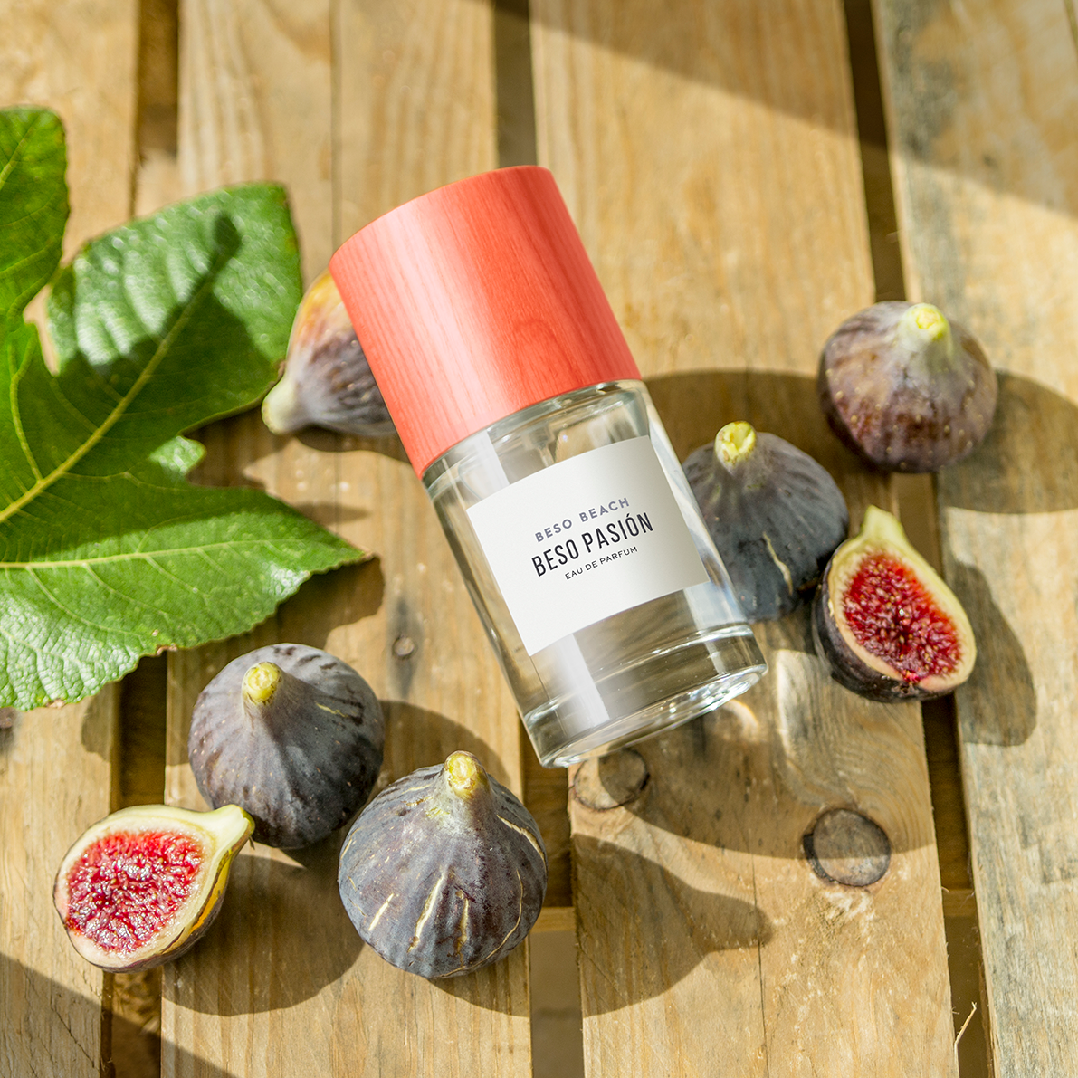 perfume bottle with figs and leaves on a wooden surface