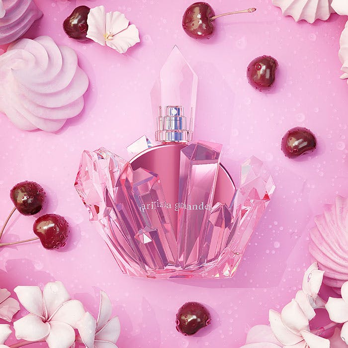 Pink perfume bottle with decorative elements on a pink background