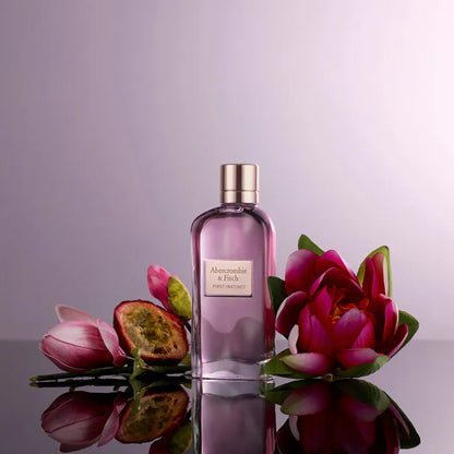 Perfume bottle with pink flowers on a reflective surface