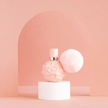 Pink perfume bottle on a white pedestal against a soft pink background