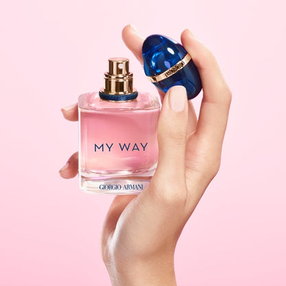 Hand holding a pink Giorgio  perfume bottle labelled 'My Way' against a pink background