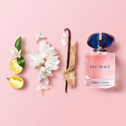 Giorgio 'My Way' perfume bottle with vanilla bean, lemon, and flowers on a pink background