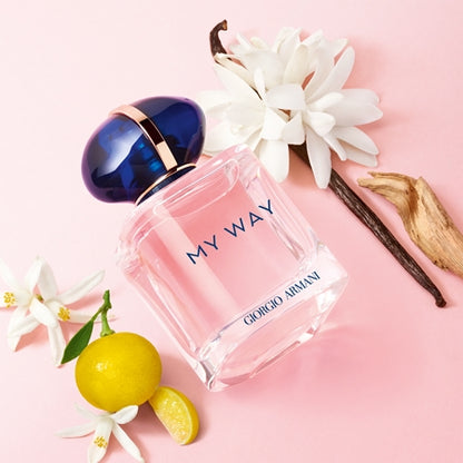 Giorgio 'My Way' perfume bottle with flowers and a lemon on a pink background