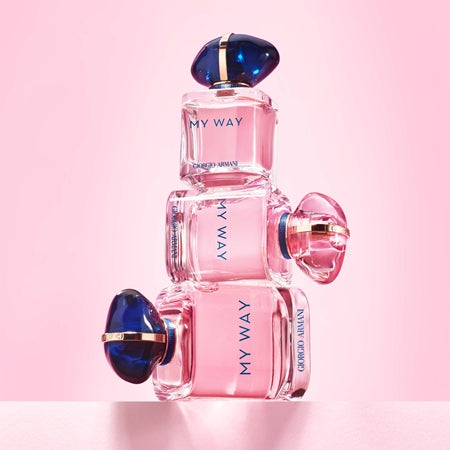 Three pink perfume bottles with blue caps on a pink background