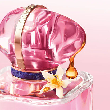 Pink perfume bottle with a flower and droplet on a pink background