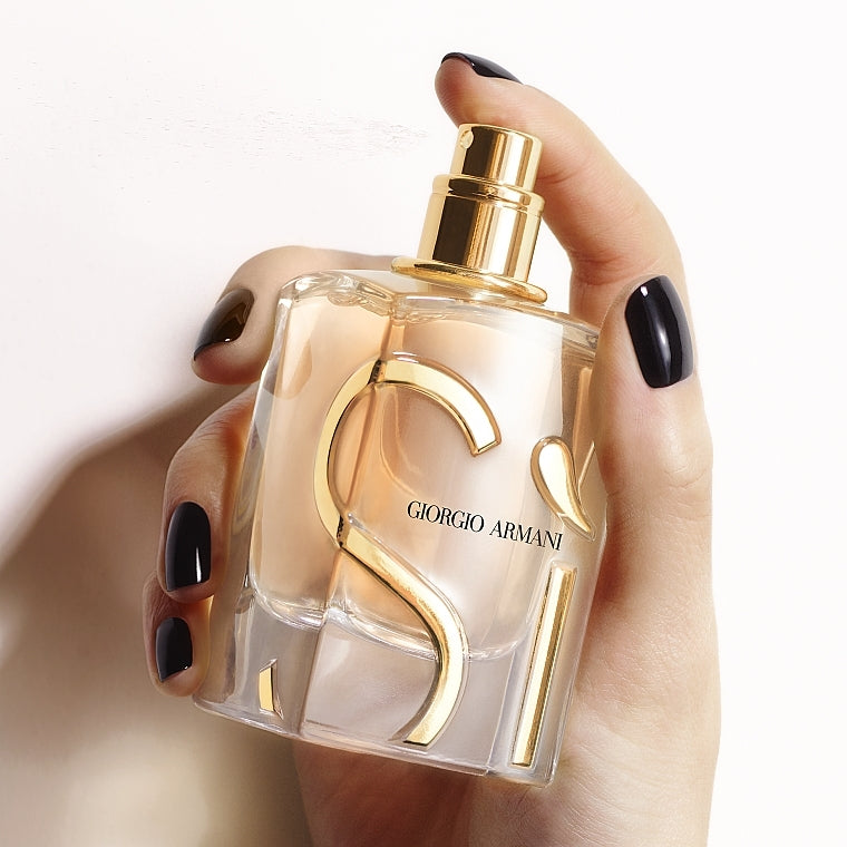 Hand holding a Giorgio perfume bottle with a gold cap.