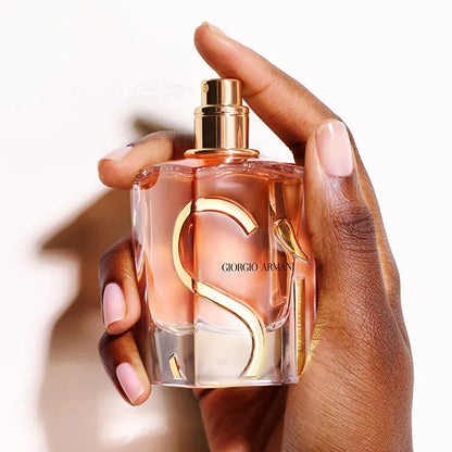 Hand holding a Giorgio Armani perfume bottle with a blurred background