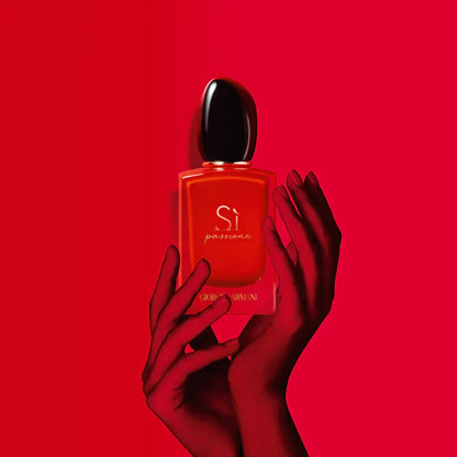 Red 'Si passione' perfume bottle held by a hand against a red background