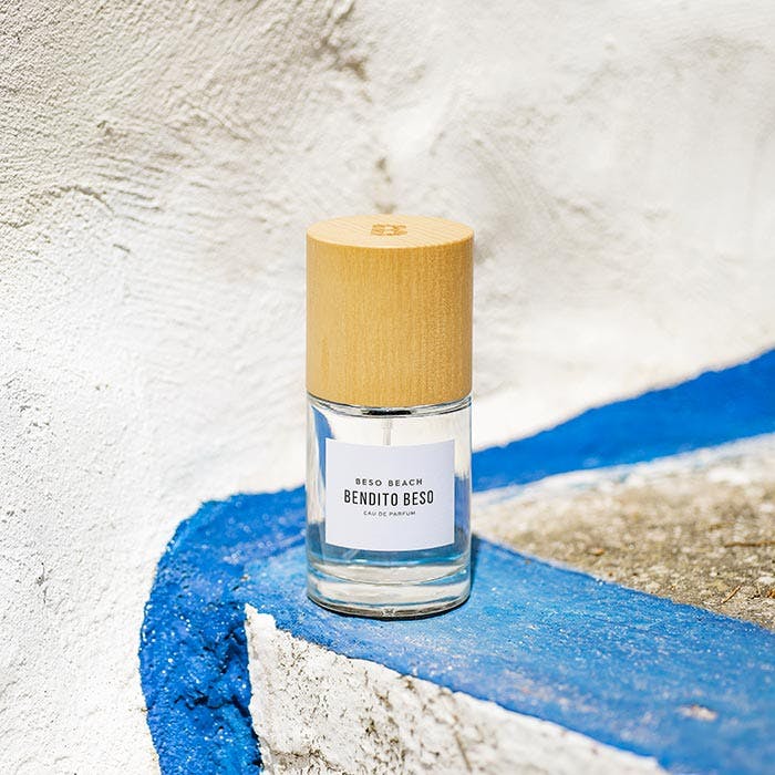 Bottle of perfume with a wooden cap on a textured surface.