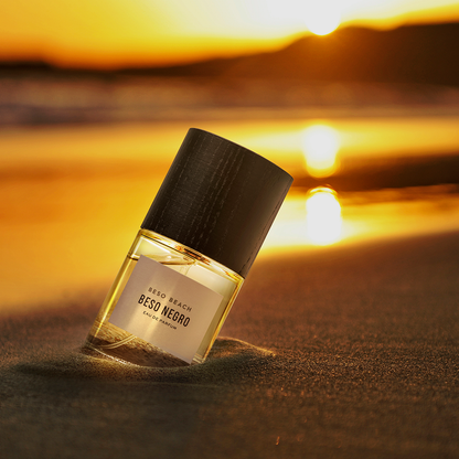 Perfume bottle labeled  on a beach with sunset in the background