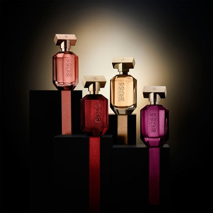 Four BOSS perfume bottles on black stands with a dark background