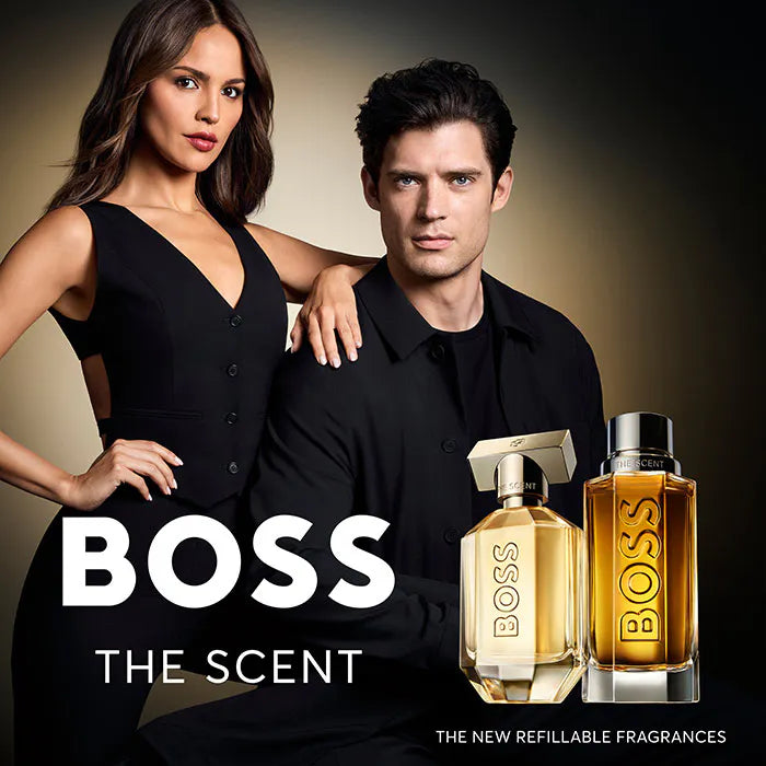 Two people posing with Boss perfume bottles against a dark background